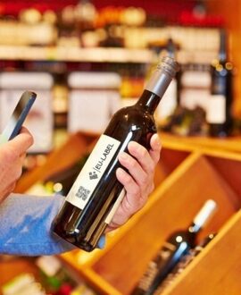 Uomo che scansiona con uno smartphone il codice QR su una bottiglia di vino - Eu-Label.info